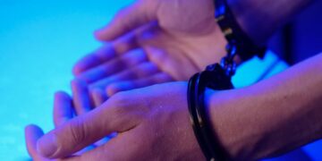 Zdjęcie przedstawia złapanego i będącego w kajdankach przestępce